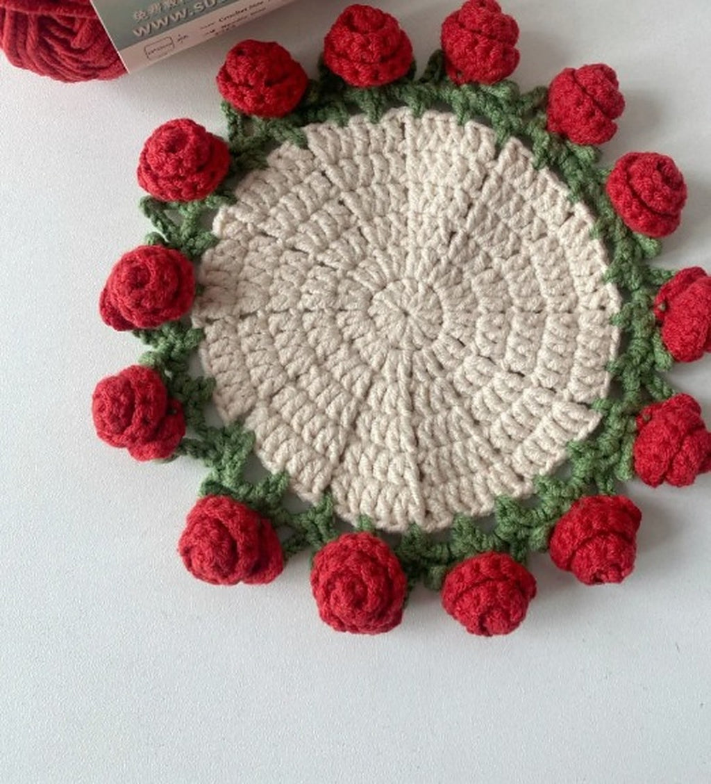 Round cream crochet coaster framed by 14 red roses and green leaves